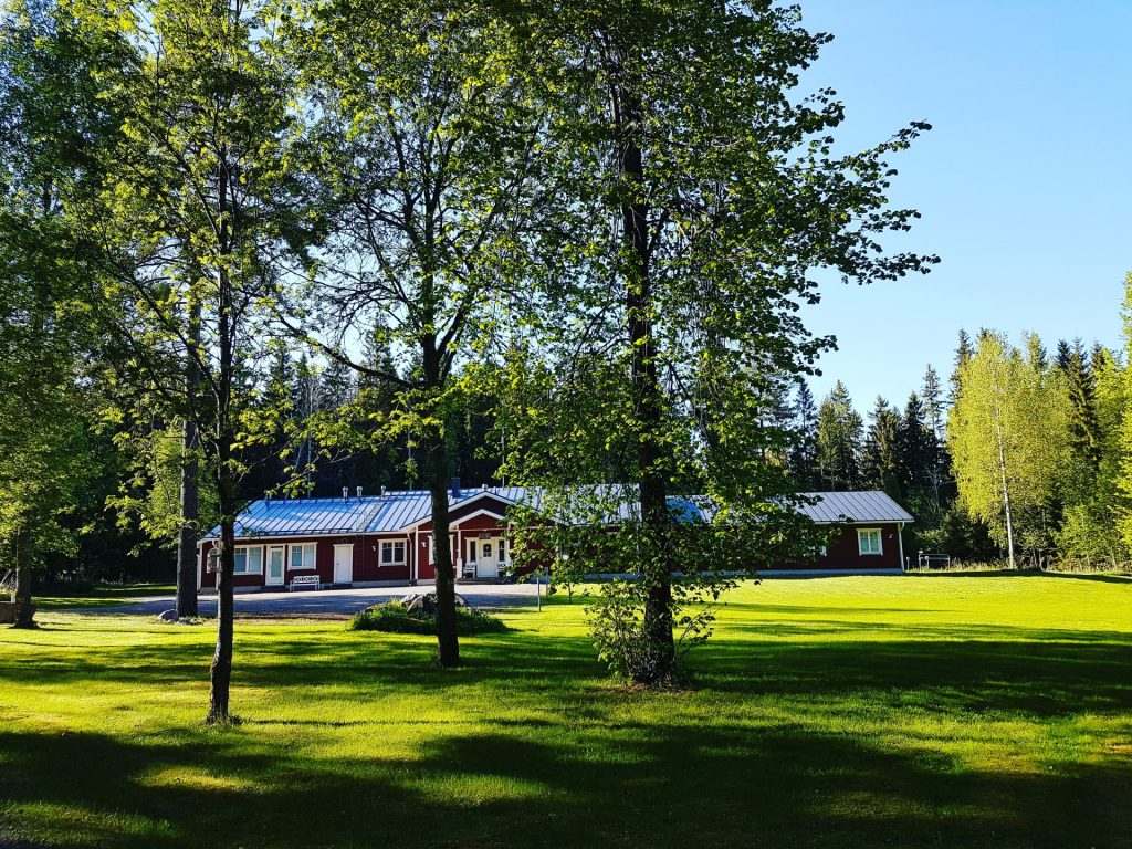 Punainen majatalo ja vihreä pihapiiri.
