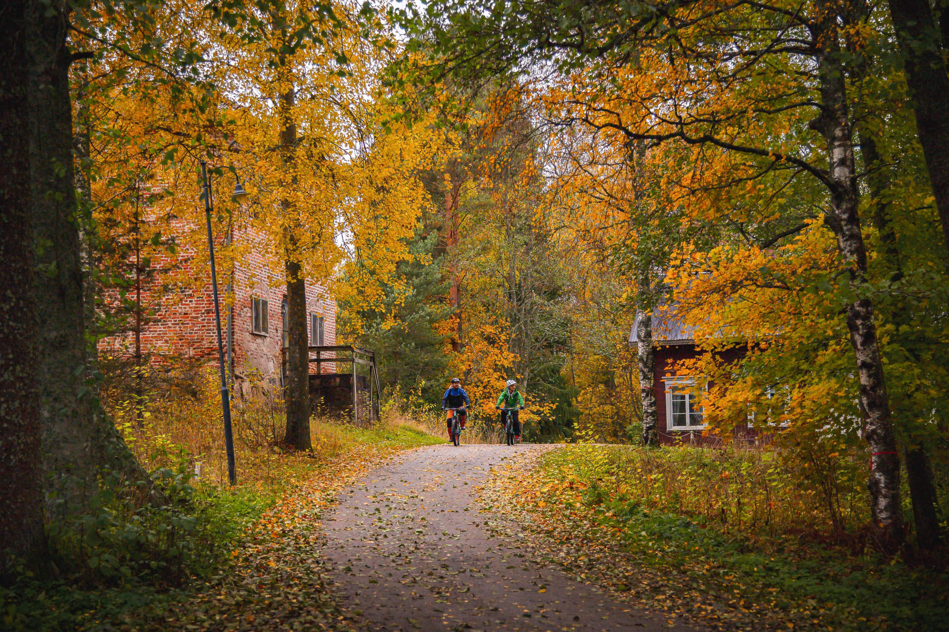 Two cyclists in the Autumn Colours of Kirjakkala Ironworks Village.